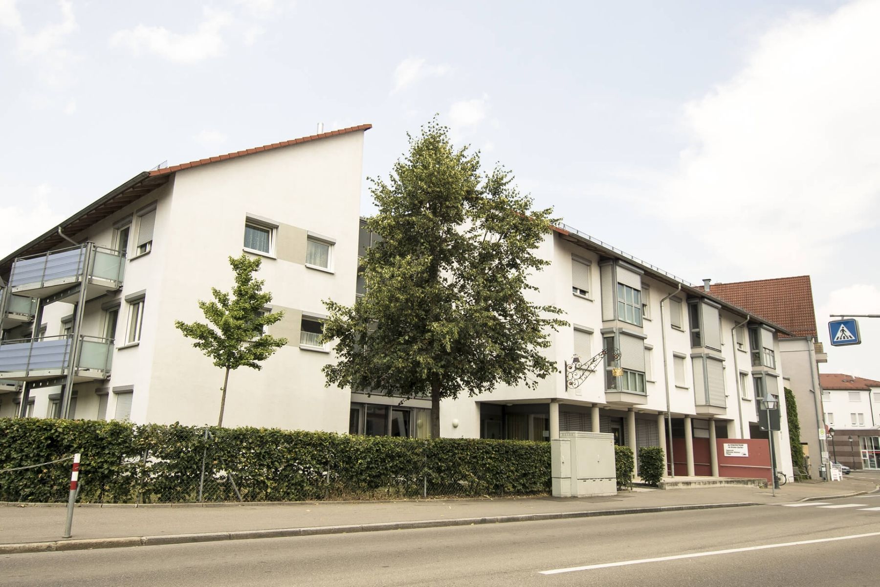 Straßenansicht eines gepflegten Pflegeheims mit Vorgarten und Gehweg.